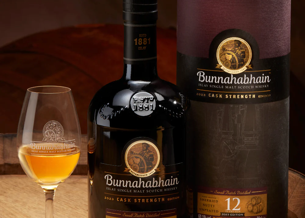Bottle, glass, and box of  Bunnahabhain 12 Year Old Cask Strength (2023 Release) scotch on a table