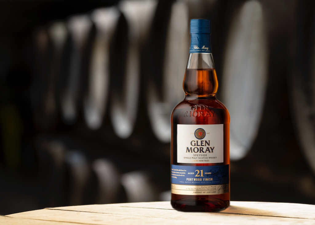 Bottle of Glen Moray 21 Year Old Portwood Finish scotch with wooden barrels in background
