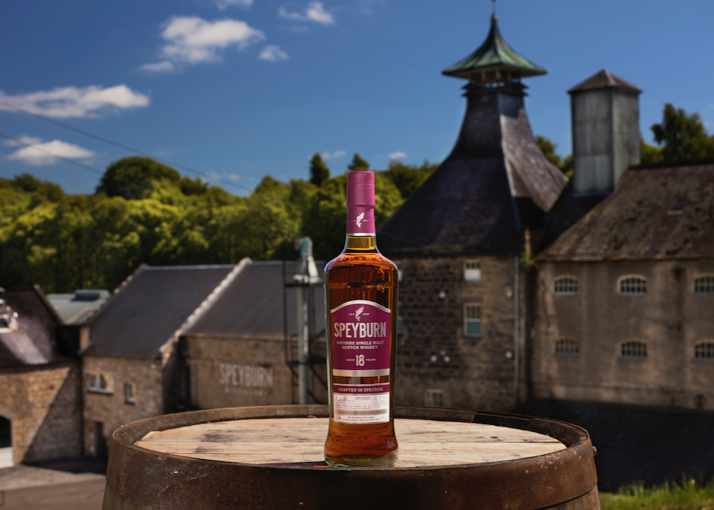 Bottle of Speyburn 18 Year Old scotch whiskey on a table with a cityscape in the background