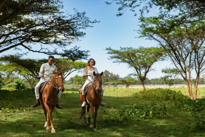 Two people riding horses at African resort in Kenya